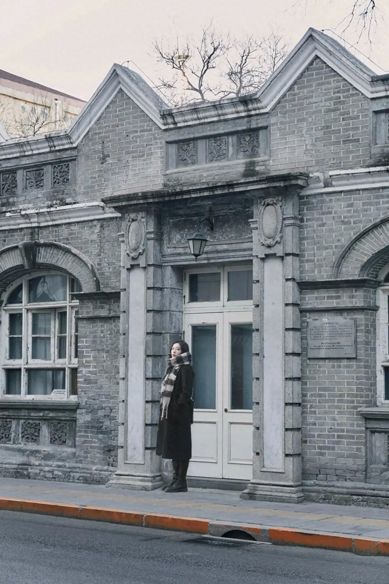 The model leans against the door frame while the photographer steps back and stands on another road. Equipment settings: Sony RX7. Pose suggestions: Looking or not looking at the camera is fine; facing the camera sideways adds a cinematic feel. Recommended shooting time: Around 4:00 PM for the best lighting. Wardrobe suggestions: The architectural style here is unique; wearing black, white, or gray, simple and minimalistic outfits work well. Additional tips: There is a lot of traffic here, so be sure to avoid vehicles while taking photos.