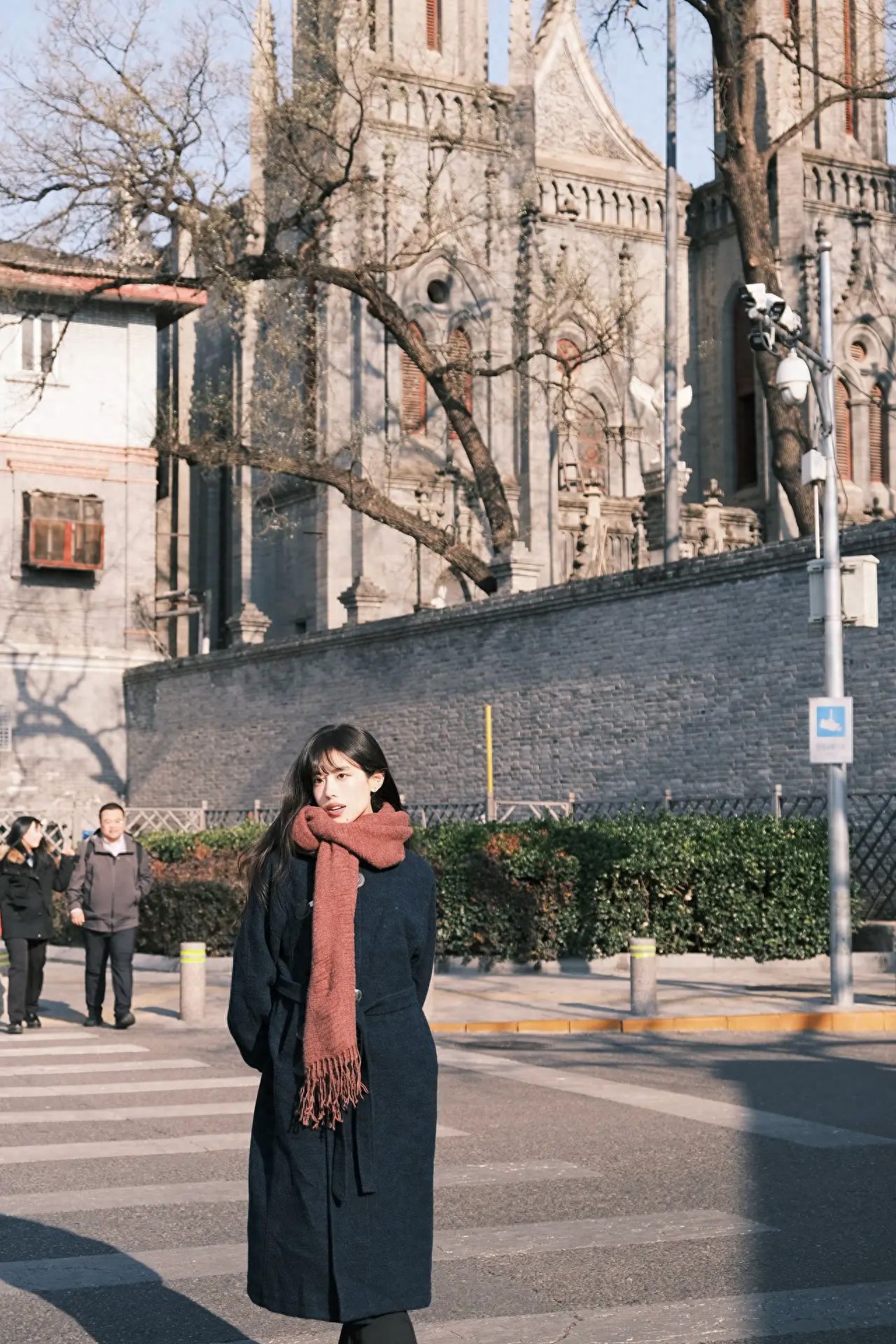 Place the subject in the foreground of the frame, using the street as a leading line to guide the viewer's gaze towards the church in the background. This composition creates a sense of depth while highlighting the relationship between the person and the architecture.

Equipment settings: Fuji XT30II, lens 18-55.

Outfit suggestions: Opt for clothing colors that coordinate with the church background, such as a black coat and a brown scarf. This will visually blend the subject with the background while keeping them prominent, avoiding overly bright or patterned attire to prevent distraction.