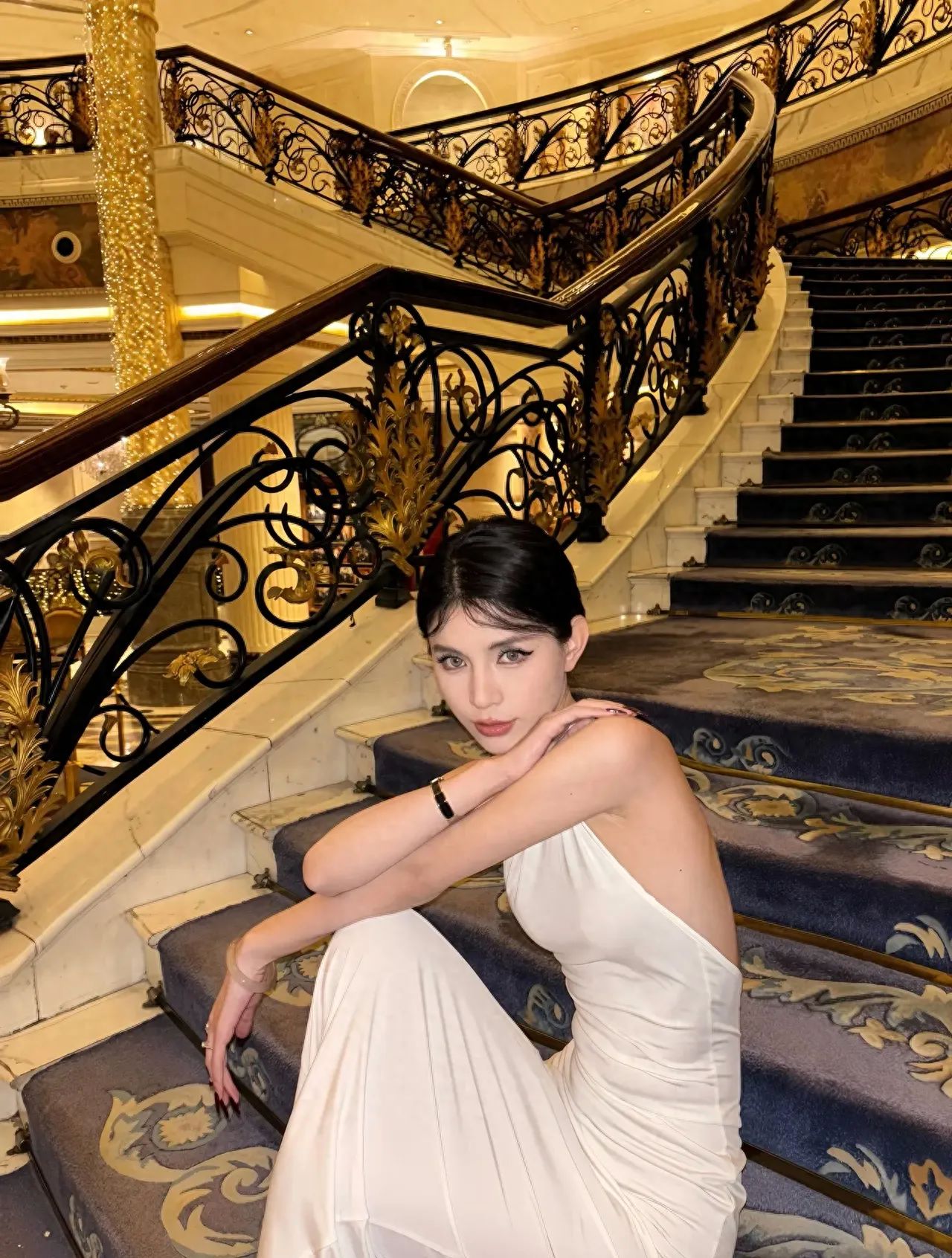 The model is sitting on the middle step of the staircase, with the photographer two steps below the model, slightly looking up using a standard lens to capture the model.

1. Outfit suggestions: A white dress matches perfectly with the staircase; you can wear a short skirt. The indoor heating is sufficient, so there's no need to worry about the temperature.

2. Other tips:
   ① Try to avoid using flash as much as possible;
   ② You can start taking photos as soon as you enter the hotel lobby without any need to make a purchase.