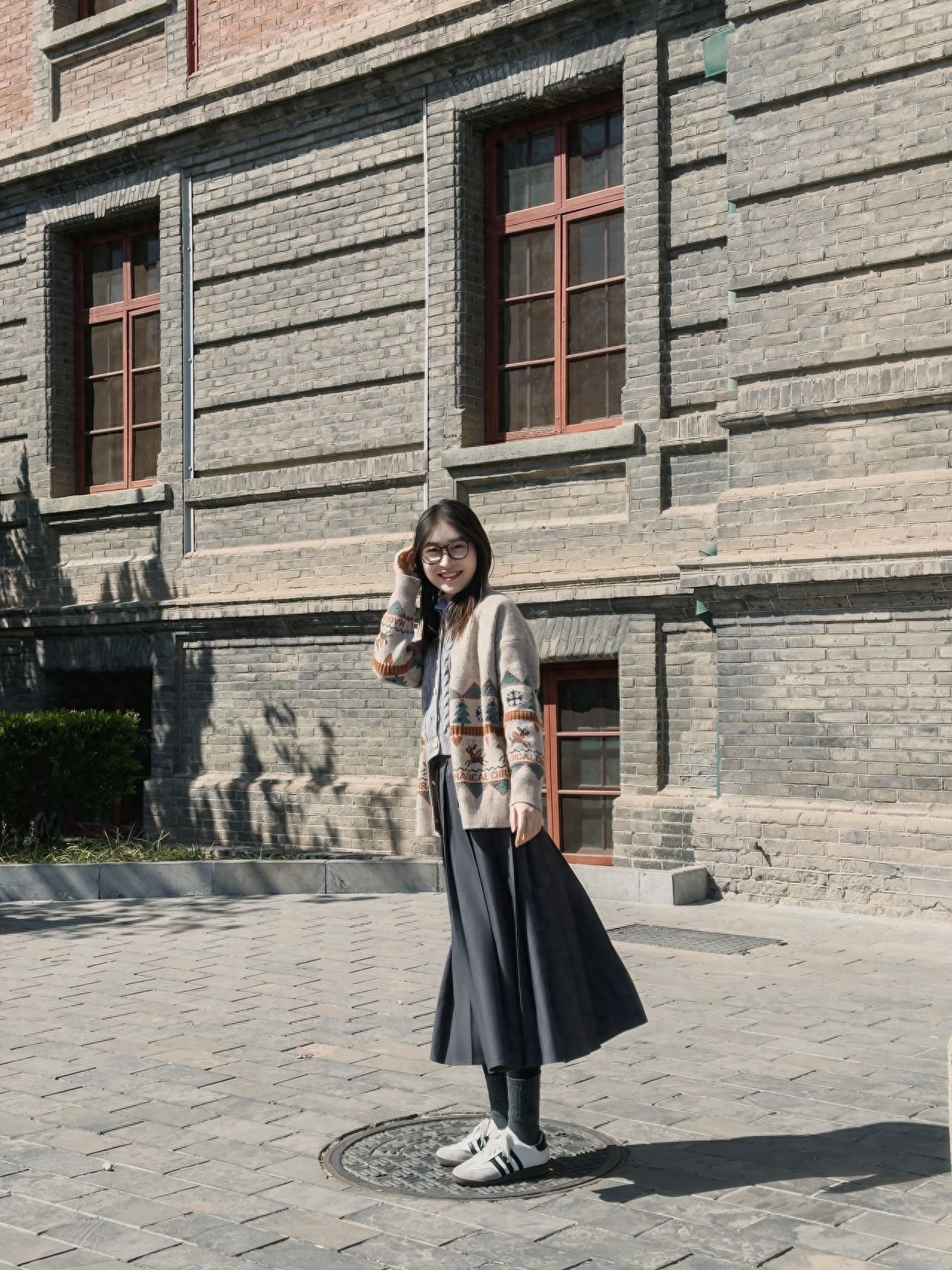 The model stands in front of the building, with the photographer standing face-to-face, maintaining a distance of 3 meters, and using a 70mm focal length, placing the model in the center of the frame.

1. Posing Suggestions:
   a. The model stands in front of the square, with both hands naturally in the pockets, looking up slightly, with eyes gazing into the distance or directly at the camera;
   b. The model has one hand in the pocket while the other hand hangs naturally, striking a pose as if walking forward to add a sense of natural spontaneity.

2. Outfit Recommendations: Opt for a top with a French romantic style, such as a blouse with ruffles or pleated designs, paired with a Chinese-style jacket. For bottoms, choose high-waisted jeans or a long skirt.