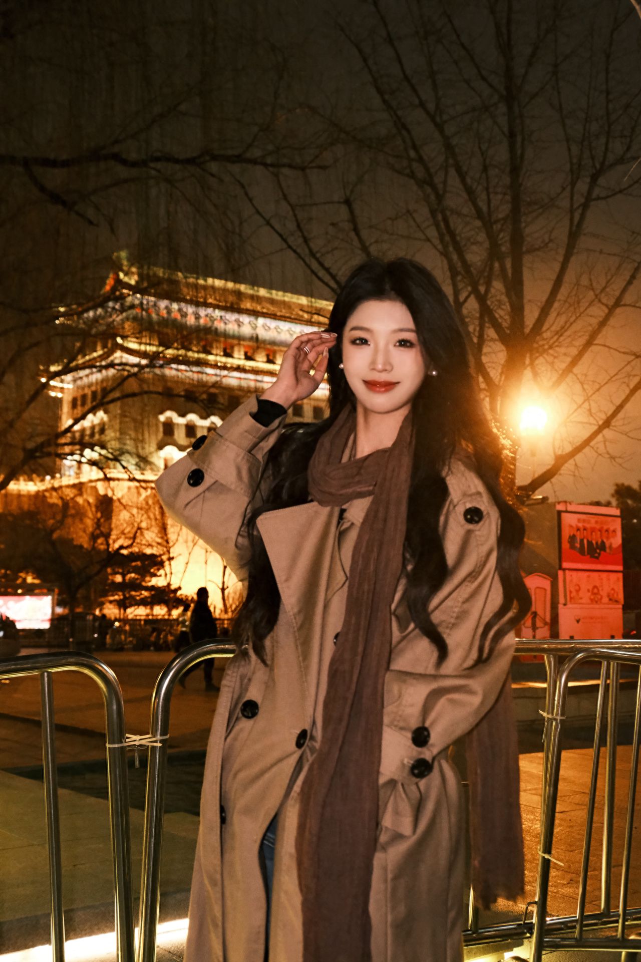 For a full-body shot of the model with the background, the photographer should slightly squat to adjust the camera position, shooting from 3 meters to the left front of the model at a slight upward angle, ensuring that both the model and the main building behind are fully incorporated into the frame to enhance the sense of depth. A centralized composition should be used, placing the model in the center of the frame to highlight the main subject. It is recommended to use a 35mm focal length for cameras or 1x for smartphones, which retains background details while emphasizing the model.

1. Equipment settings: ISO 6400, f4.3.
2. Shooting tips: It is suggested to shoot after 7 pm, and remember to bring a flash for the best results.
3. Dressing suggestions: Light or bright colored clothing is recommended.
4. Other tips: Avoid having the model stare blankly into the camera; try capturing them looking in other directions. For those who may experience oily skin issues, it's a good idea to prepare some loose powder for touch-ups.