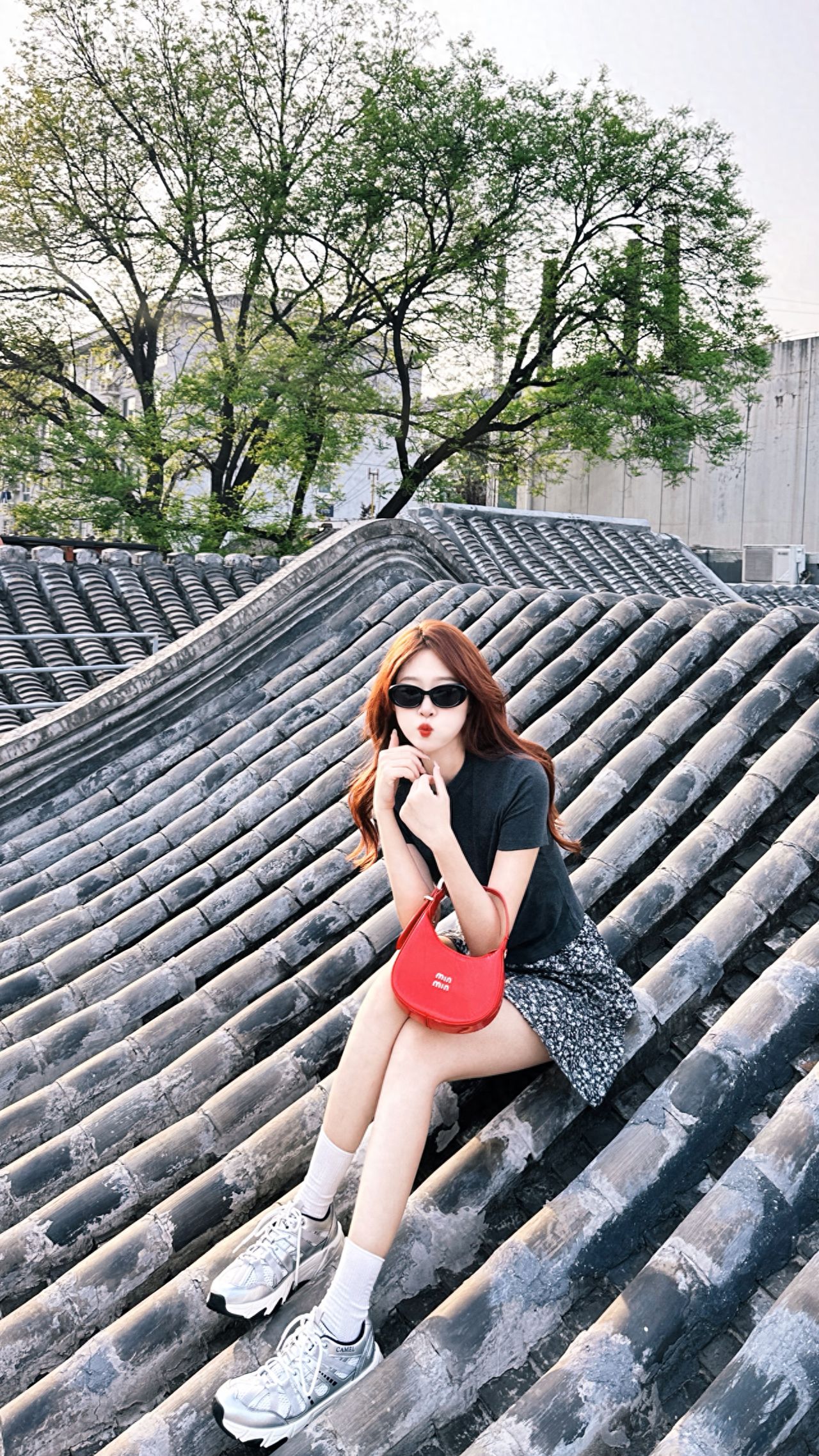 The model sits on the rooftop tiles, and the photographer takes a horizontal shot from a slightly lower angle, maintaining a camera position that is level with the model's line of sight. Using a 35mm lens on a camera or a 1x focal length on a smartphone allows for capturing the model's details while retaining the texture of the tiles and the background environment. 

Posing Tip: The model should sit naturally with slightly bent legs.