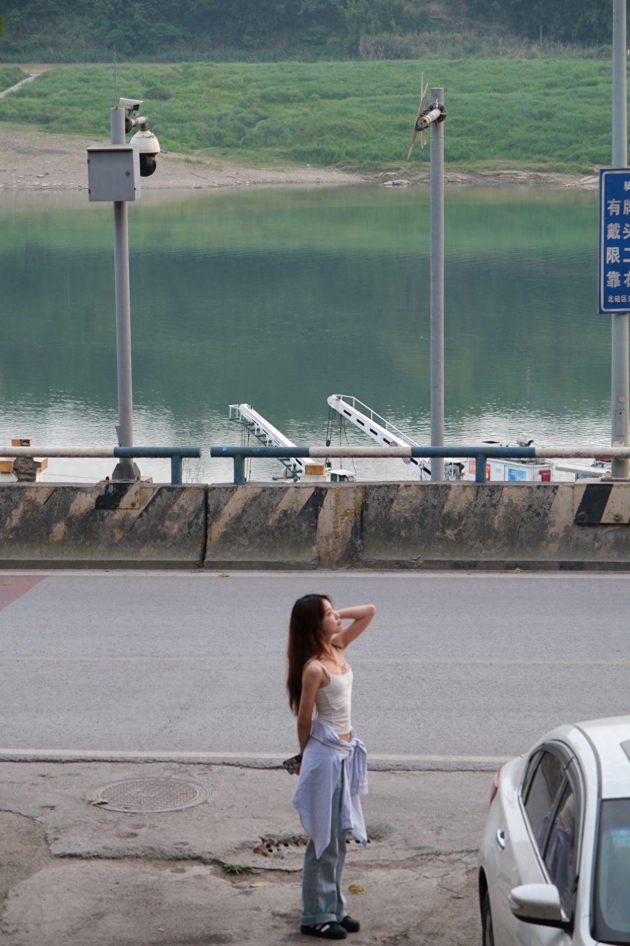 The model stands by the roadside, with the photographer positioned above on the stairs, shooting from a high angle, with the model slightly lower in the center of the frame, appropriately showing the background's sense of depth, using the rule of thirds composition, the model is slightly lower in the middle of the frame, with the Jialing River and buildings forming a horizontal dividing line in the background, enhancing the balance of the image.

1. Photography poses:
   ① Stand by the roadside, one hand raised and placed behind the head, the other hand behind the back;
   ② Stand by the roadside, body straight, head turned to one side, gaze in that direction, one hand hanging on the side of the body, holding an object;
   ③ Lean against a lamppost by the roadside, side face looking towards the river.

2. Other tips: Pay attention to traffic safety, do not affect vehicle passage while taking photos, if shooting at night, bring a tripod to ensure photo clarity.