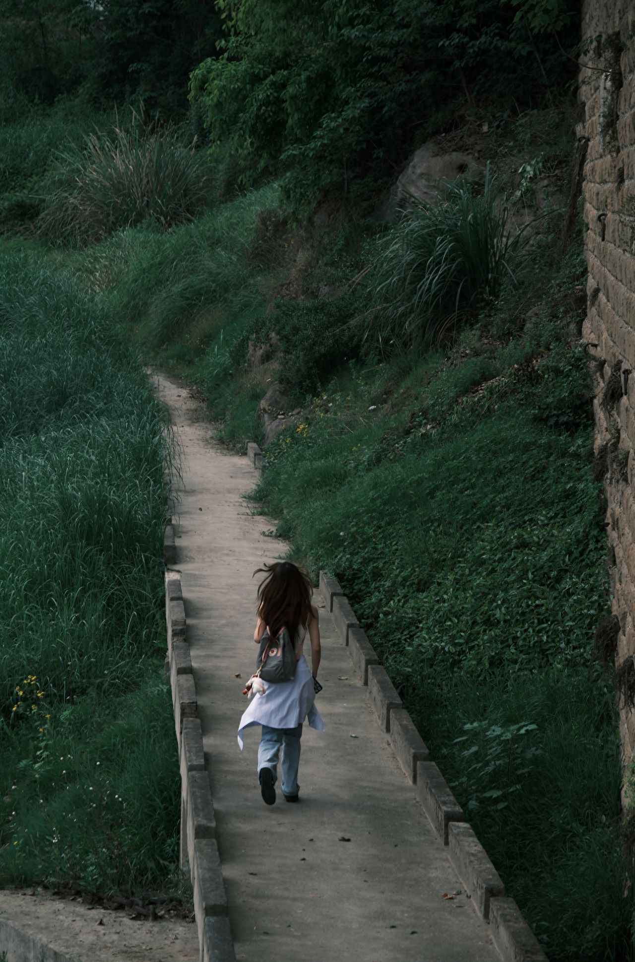 The model stands in the middle of the path, facing away from the photographer, who is positioned slightly behind and above the model to create a sense of depth and natural atmosphere. The model is centered in the frame, with the surrounding greenery and stone walls providing a contrast that highlights the subject. A telephoto lens is used to compress the sense of space, emphasizing the layers of the subject and the background.

1. Photo poses: Capture the dynamic movement of a natural walk; pause to gently touch the flowers and plants, showing a relaxed and enjoyable mood; lean against the greenery with eyes closed, basking in the sunlight to create an atmospheric feeling.

2. Travel tips: Visit in the morning or afternoon when the light is soft, suitable for capturing natural and fresh style photos. Avoid midday when the sunlight is too strong, which can lead to overexposure in photos. Check the weather in advance, as rain can make the paths muddy, but also create a unique fresh atmosphere. Wear comfortable shoes that are easy to walk in.