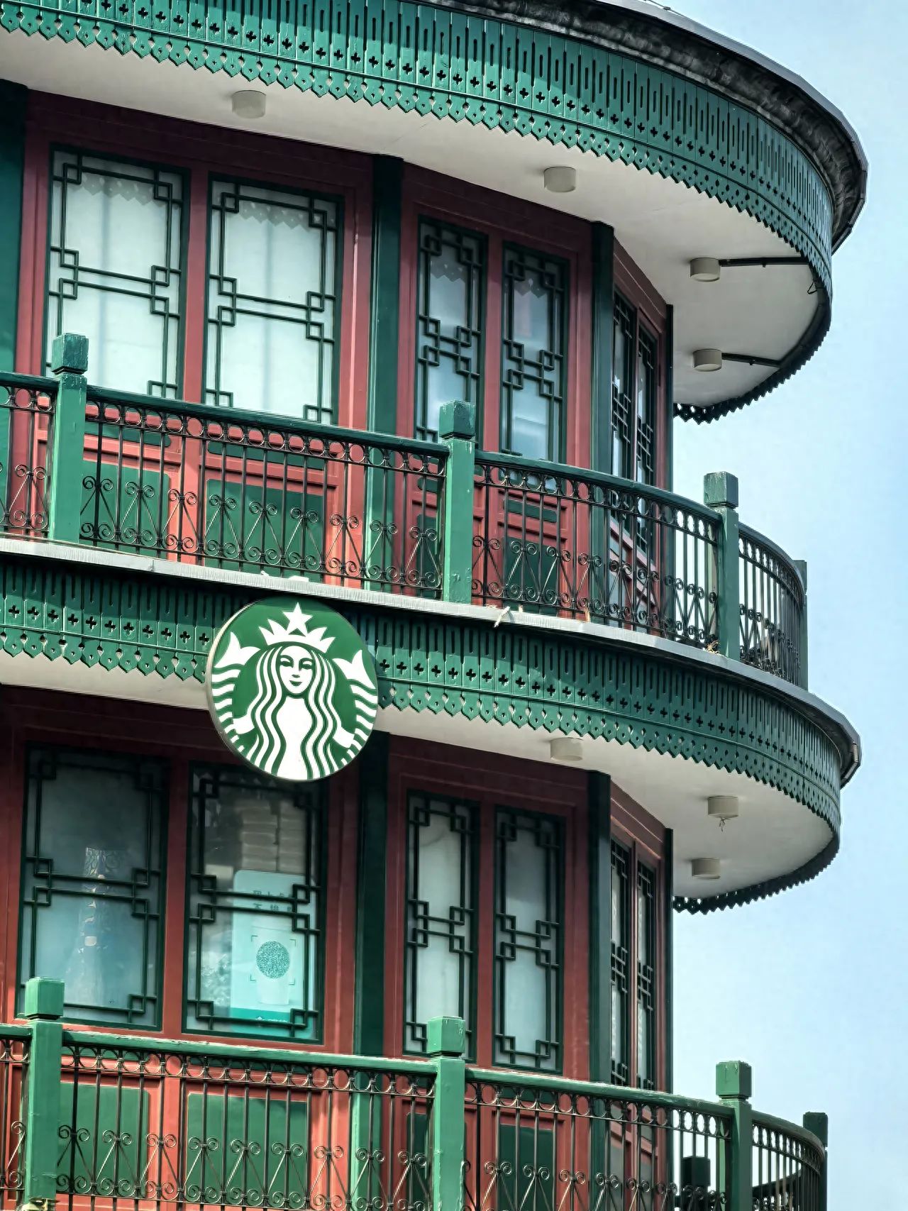 The photographer stands at an oblique angle to the building, capturing from a low angle looking up. The building's windows, railings, and other elements naturally form a frame, enhancing the structural and layered feel of the image. A wide-angle lens is recommended, as it can capture a broader scene, strengthening the visual tension and sense of space of the building.