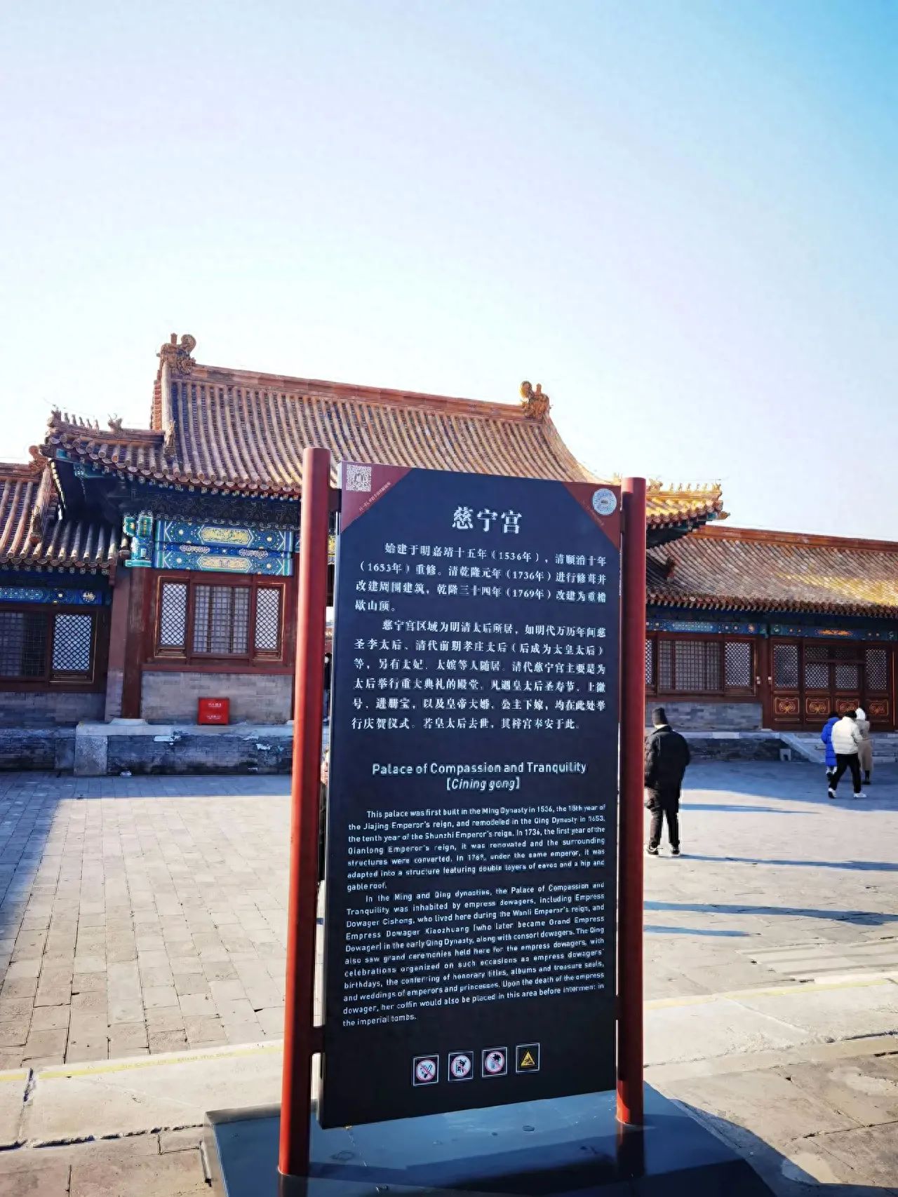 The photographer stands in front of the introduction sign, at a lower level angle, ensuring that both the sign and the background buildings of the Cining Palace are fully captured in the frame. The composition uses a central framing technique, placing the Cining Palace introduction sign at the center of the image to highlight the main subject; meanwhile, the background architecture is used to create a呼应, enhancing the historical and cultural atmosphere of the scene. It is recommended to use a wide-angle lens to include a larger scene, ensuring that the text on the introduction sign and the details of the background architecture are clear, showcasing the spatial environment.