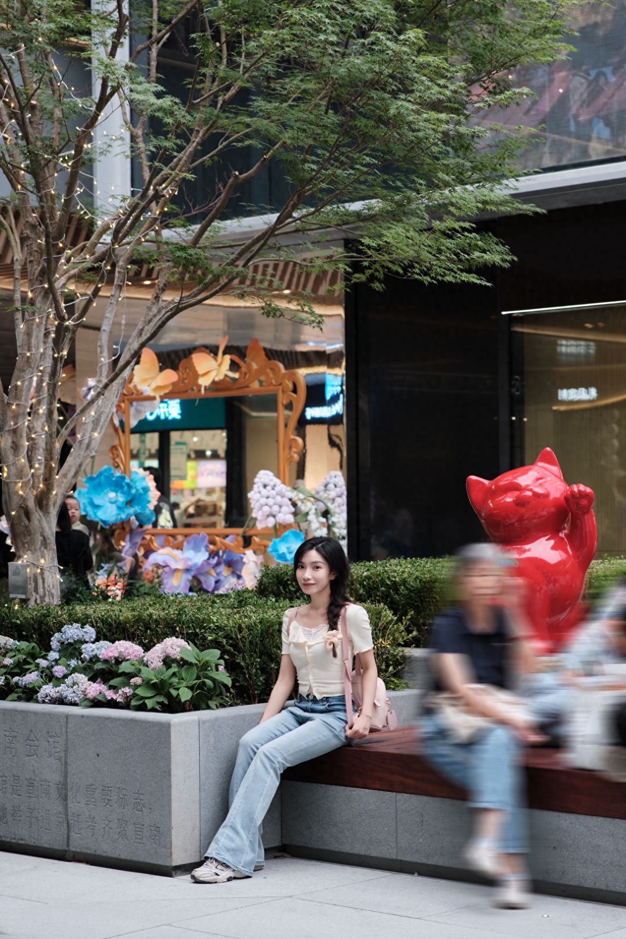Photo by Daji Alley - Red Cat Statue by the Flower Bed