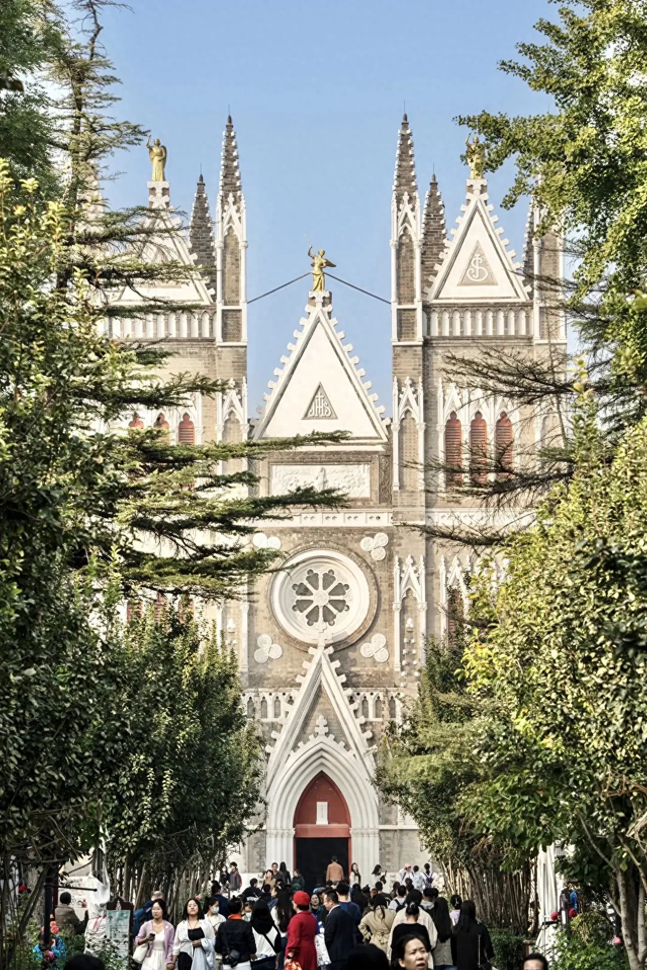 Photo by Xishiku Catholic Church - The front facade of the church building with trees.