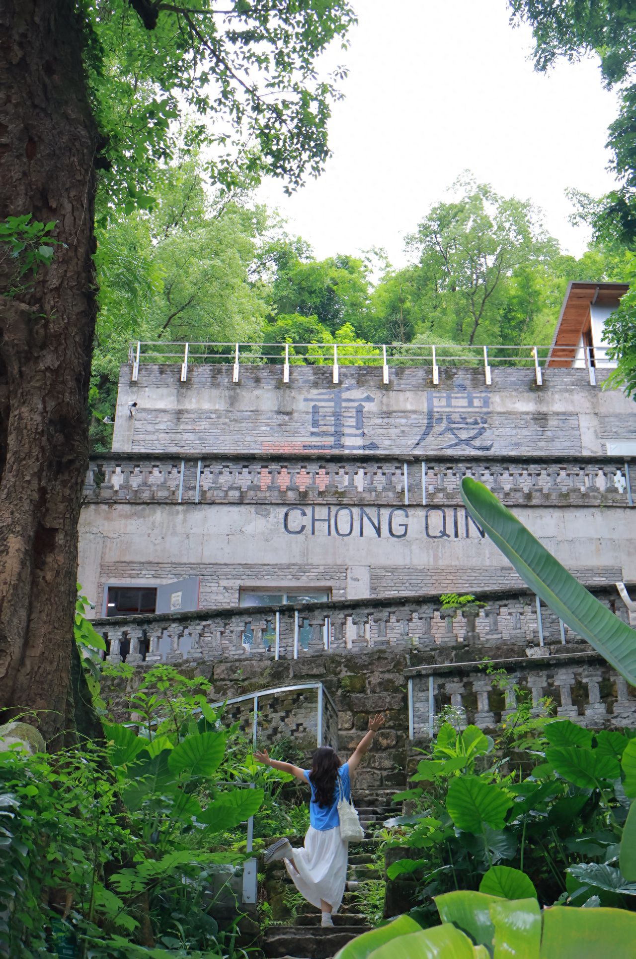 1. The model spreads their arms wide and strides upward as if embracing the entire mountain city! This captures the fervor of "rushing to Chongqing," echoing with greenery and old architecture, exuding an overflow of vitality! 🌿

2. Seated, the model lightly raises their arm, looks up at the architecture, and effortlessly transitions into an "immersive experience" mode. From "rushing" to "listening," the change in posture tells a wandering story, adding a sense of progression to the scene, and filling the atmosphere with a vivid sense of place. ✨

Check-in Tips:
Choose a sunny morning (9 - 11 AM) when sunlight dapples through the leaves, adding a natural filter to the image; on cloudy days, use the soft light to capture a mystical, forest-like ambiance, avoiding harsh midday light that could overexpose the subject's face!

Photography Strategy:
Use the greenery on both sides of the stone steps as a natural frame, centering the person and the "Chongqing" wall, highlighting the depth of the scene; shoot from below the stone steps, allowing the "Chongqing" wall to dominate the upper half of the frame, with the person stretching below, reinforcing the feeling of insignificance and blending with the mountain city forest.