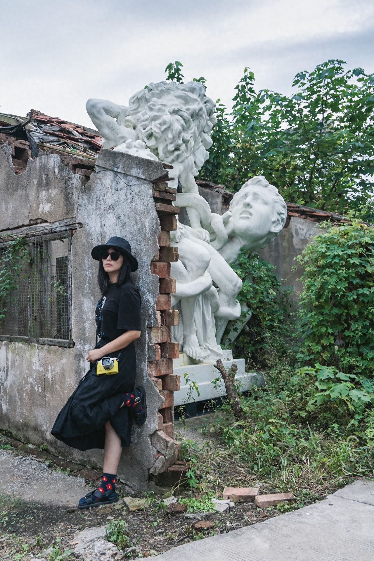 Use the rule of thirds to place the subject on the left third of the frame, with the David statue in the center, and include greenery on the right to create a sense of depth; the model leans against the wall while the photographer stands directly in front, shooting at eye level. 1. Pose: The model leans against the wall and looks at the camera; 2. Wardrobe suggestion: It is recommended to wear black series clothing.