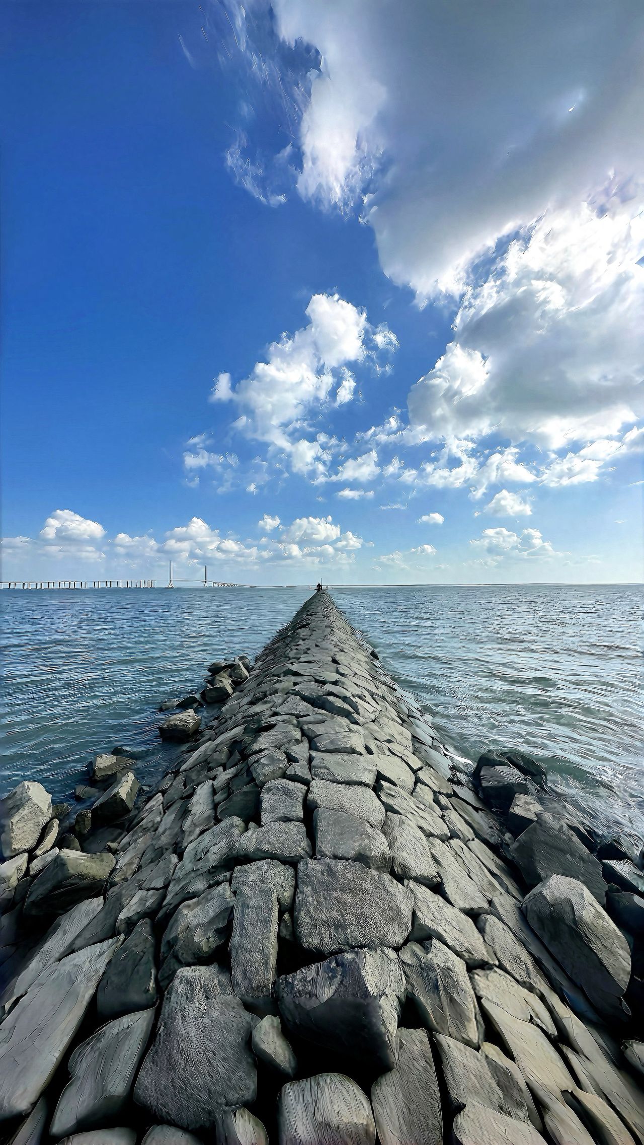 Using the wide-angle mode on the Apple 16 Pro Max, frame the blue sky, ocean, and road within the same shot. Pay attention to choosing a good weather day for the shoot, and with a press of the shutter button, you can capture a dramatic and atmospheric masterpiece.