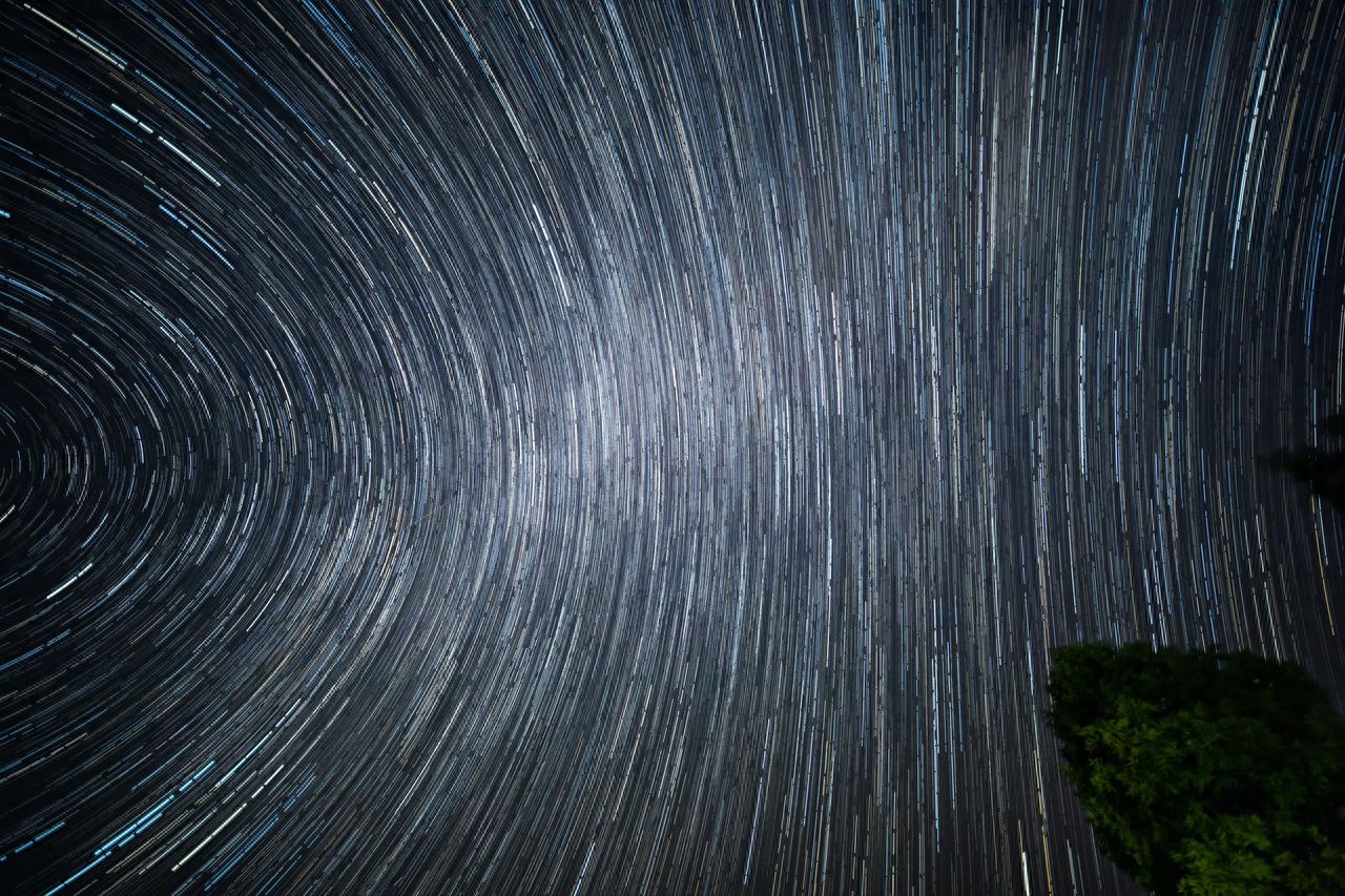 The photographer uses a low-angle shot, employing leading lines to create concentric circular lines of star trails, naturally guiding the viewer's attention. The composition should include trees on the ground at the bottom right corner to add depth to the image.

1. Equipment settings: Canon 5D Mark IV + Laowa 12mm f/2.8 + aperture f/2.8 ISO 1600 shutter speed 30s.

2. Travel tips: Choose a time around the first day of the lunar month, as there is almost no moon throughout the night.