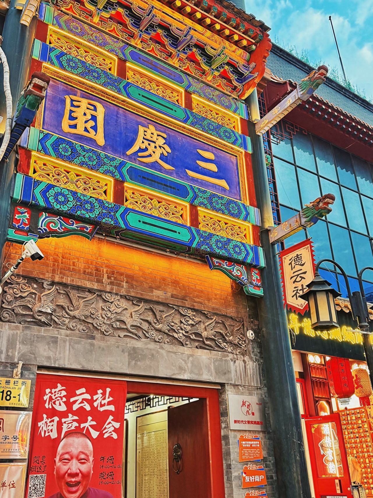 The photographer stands slightly lower in front of the Sanqing Garden shop, using a low-angle shot with a central composition to place the "Sanqing Garden" plaque in the center of the frame, highlighting the main subject. The frame includes the colorful dougong above the plaque, the brick carving patterns below, as well as the "De Yun Society" flag and lanterns on the right, enriching the layering of the image.

Travel Tips: It is recommended to take photos during clear weather with good sunlight.