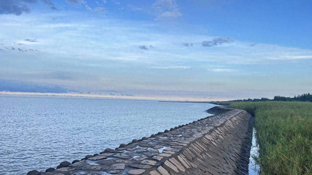The photographer uses a low angle shot, allowing the stone embankment to stretch from the bottom right corner to the distant horizon on the left, guiding the viewer's gaze and enhancing the sense of depth. The composition includes the stone embankment, a large area of lake water, the sky, and the grassland on the right, showcasing an expansive environment. It is recommended to use a wide-angle lens and stand on the stone embankment to photograph, balancing the proportion of water and sky with the sense of lines of the embankment.

Other tips: It is advised to take good sun protection measures.