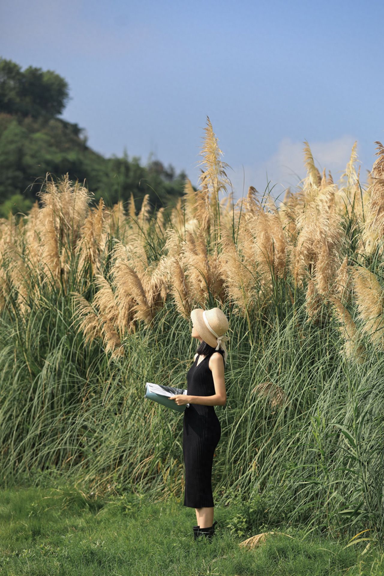 The photographer stands sideways behind the model, shooting at eye level, using the rule of thirds to divide the image horizontally into the sky above, the reed subject in the middle, and the grass below, creating a clear sense of layers. The model's black outfit contrasts with the golden reeds to highlight the subject.

Additional Tips: Fire can be used, along with tents, hammocks, and water play.