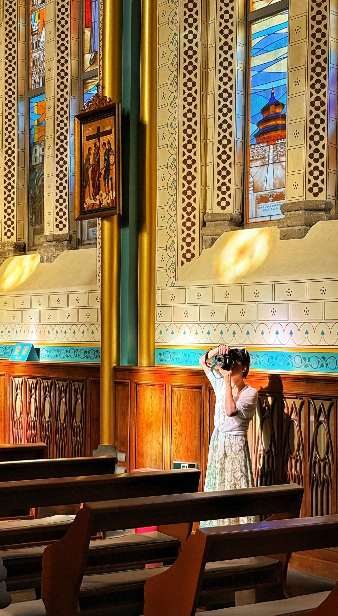 Photo by Xishiku Catholic Church - Stained glass windows and hanging paintings inside the church