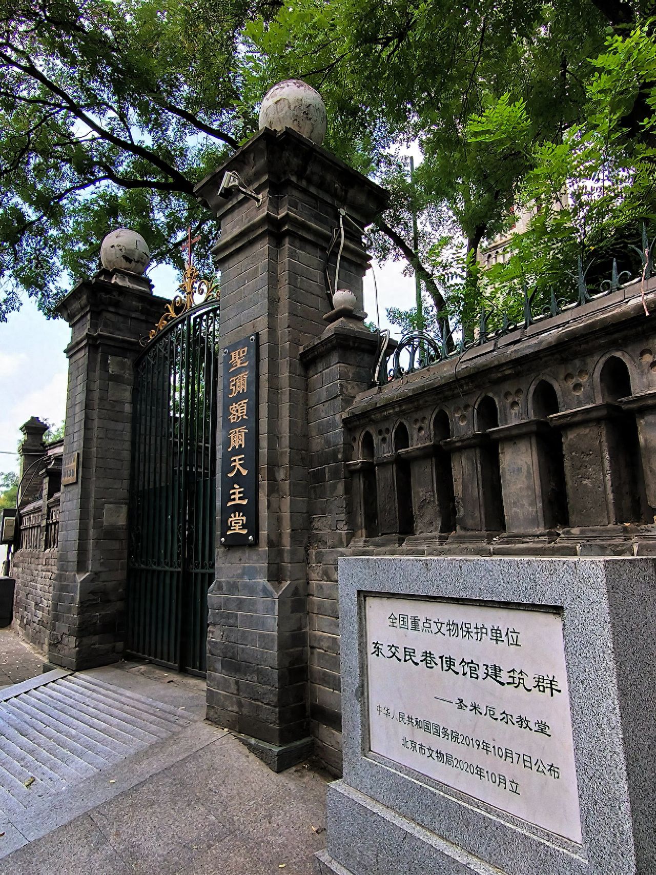 Use a low-angle shot to emphasize the three-dimensionality of the stone pillars and the stone tablet. Employ the rule of thirds in composition, placing the left stone pillar and iron gate on the left third of the frame, and the right stone tablet on the right third, achieving balance. Frame the shot to include the entrance, the "St. Michael's Catholic Church" plaque, the stone tablet, and the leaves above to add a natural atmosphere.

Shooting time: It is recommended to shoot during clear weather when natural light is good.