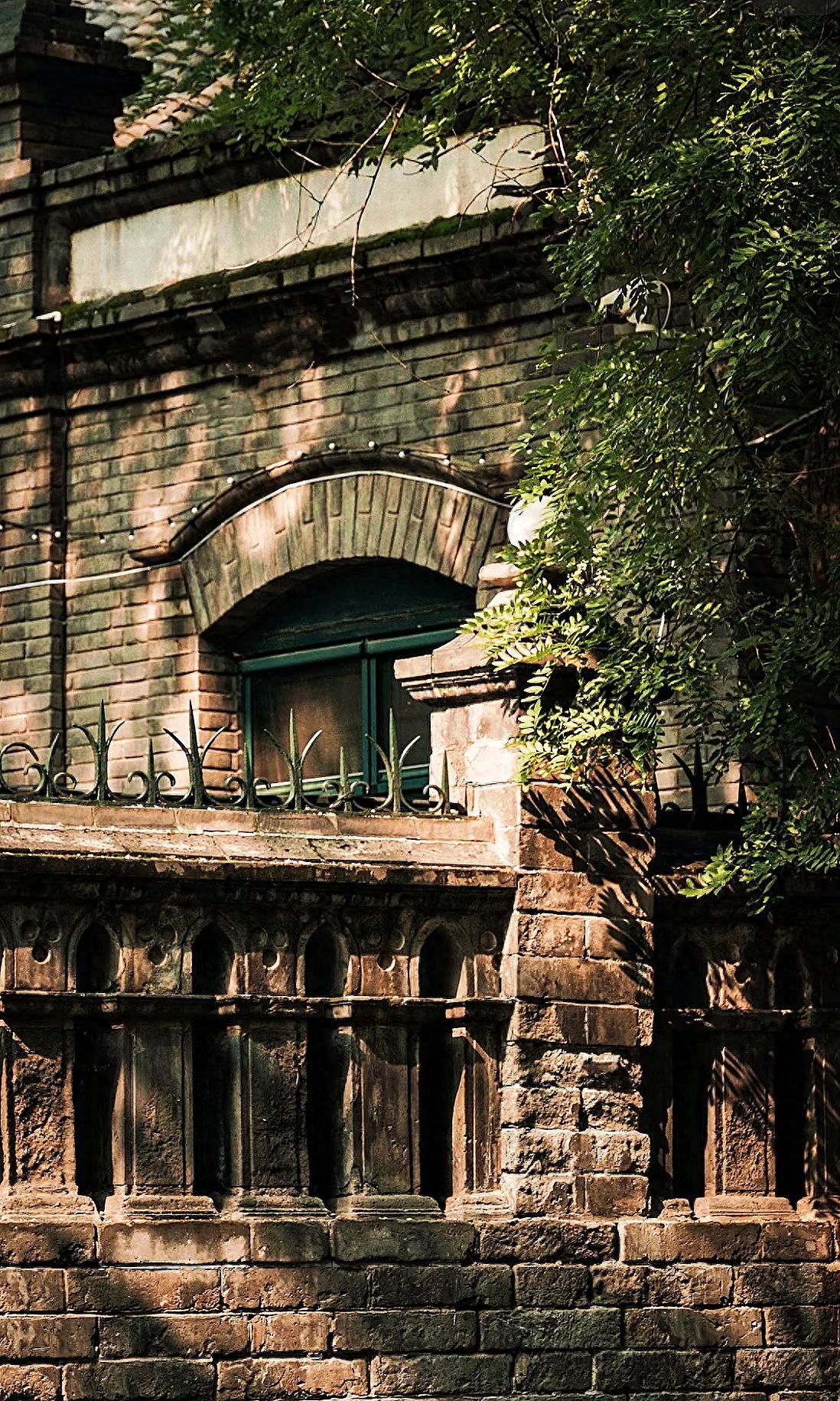 The photographer uses a low-angle shot, capturing from a lower position and pointing the camera upwards. They employ foreground composition, including green plant leaves on the right to add depth, and highlight the arched windows and texture details of the brick wall in the middle ground. The frame includes a section of the building, windows, and green plants on the right, avoiding unnecessary background. It is recommended to use a telephoto lens to compress space, making the foreground and architectural details more compact and emphasizing a vintage feel.

Travel Tips: Admission is free.