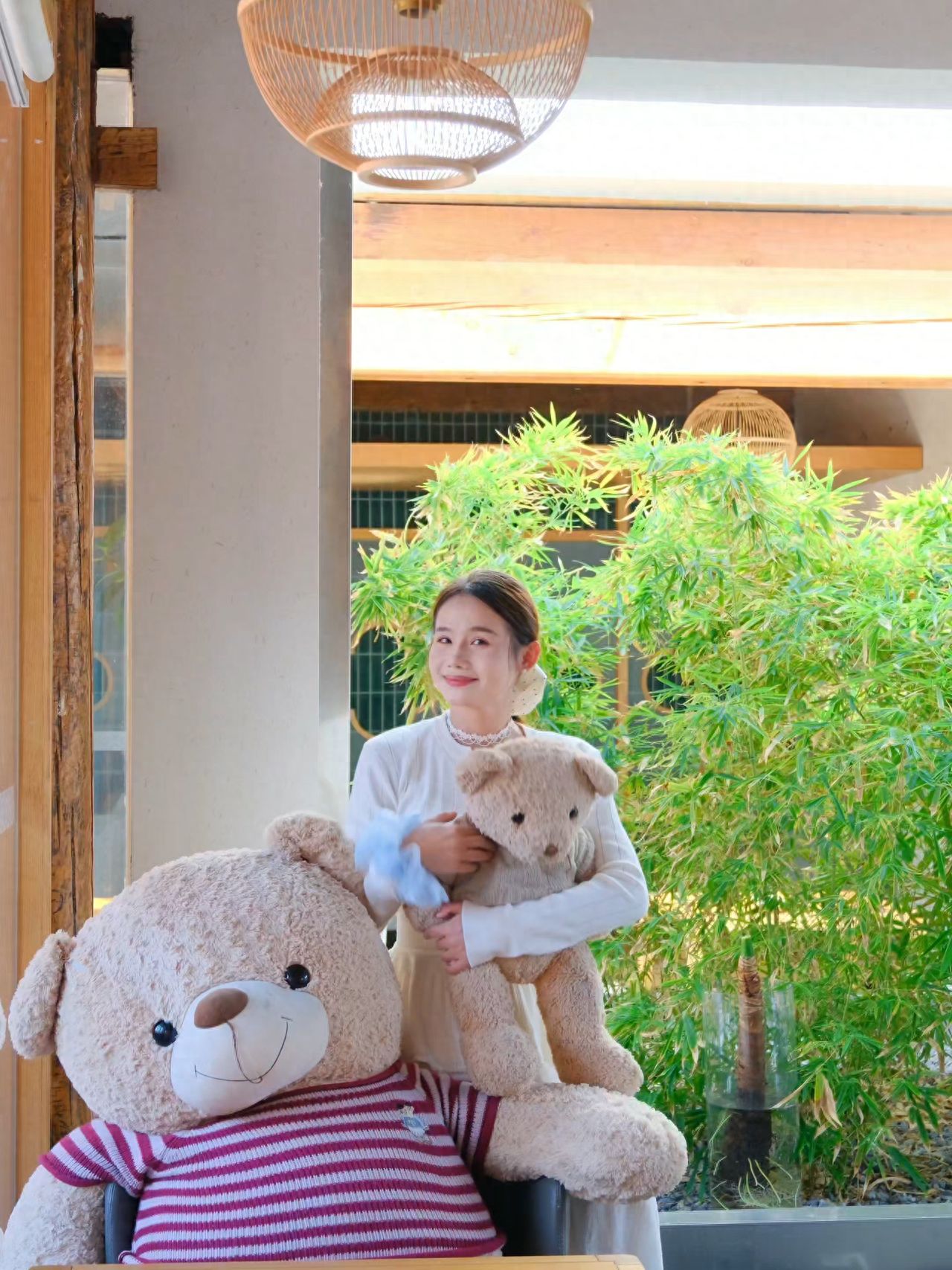 The model stands next to the teddy bear, with the photographer positioned directly in front of the model, approximately 5 meters away, using green plants as a backdrop for a frontal shot.

①Photo Pose: The model leans against the larger bear, holding the smaller bear in their hands, and looks towards the camera.

②Travel Tips: The establishment serves as a restaurant during the day and turns into a bar at night. The terrace is closed after 18:00.