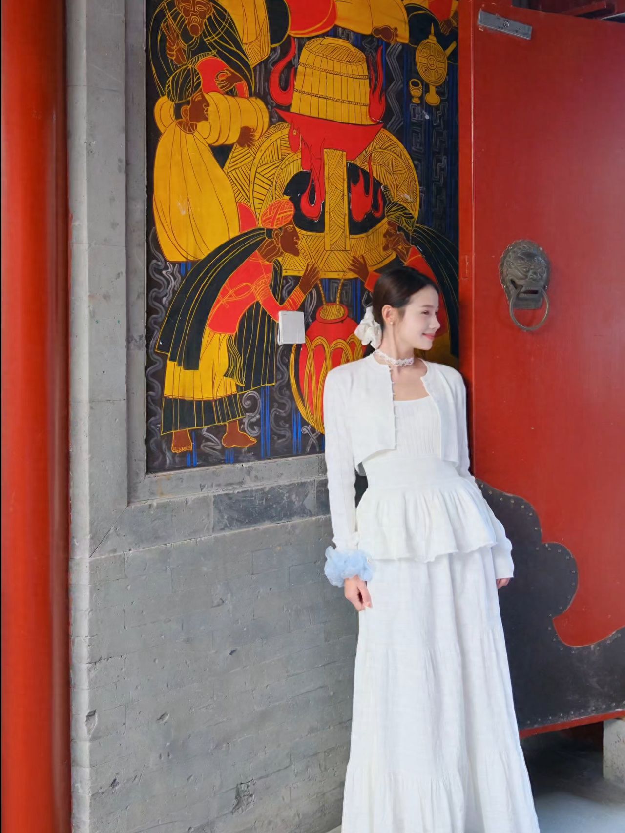 The model stands close to the mural wall, with the photographer positioned diagonally in front of the model, approximately 4 meters away. The background consists of the mural wall and a red door, capturing a slightly profiled shot.

①Photo Pose: The model leans their shoulder against the wall with both hands naturally hanging down and their face slightly turned.

②Travel Advice: The venue operates as a restaurant during the day and transforms into a bar at night, with the terrace closing after 18:00.