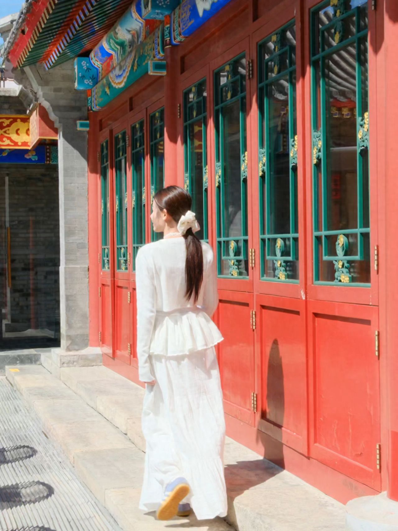 Model stands on the steps, with the photographer positioned directly behind the model, about 4-5 meters away, using the red wooden door as a backdrop, shooting from the side.

1. Pose for the photo: The model faces away from the camera, strides forward along the steps, capturing the moment.

2. Travel advice: The venue operates as a restaurant during the day and transforms into a bar at night, with the terrace closed after 18:00.