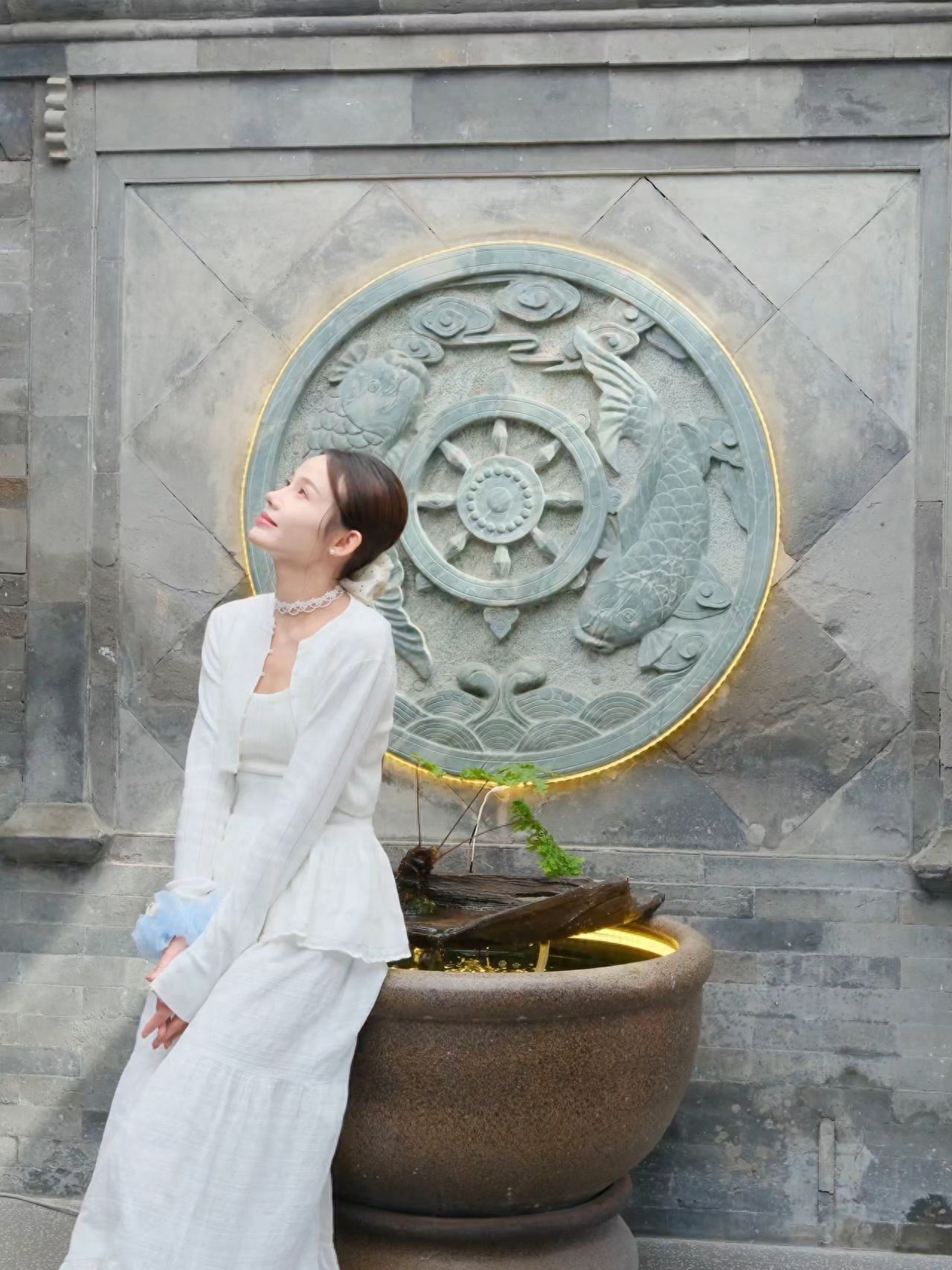 The model is sitting sideways on a water tank, with the photographer standing directly in front of the model, about 4 meters away, using the antique stone carving as a background for a frontal shot.

① Photo pose: The model is sitting sideways on the fish tank with hands clasped on the lap, head slightly raised.

② Travel suggestion: The place is a restaurant during the day and a bar at night, and the terrace is closed after 18:00.