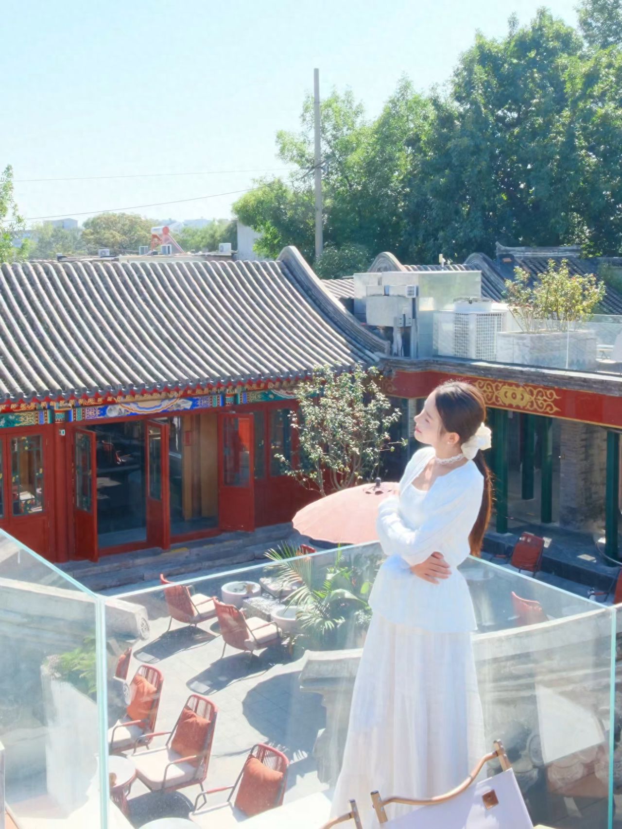 The model stands next to the fence, with the photographer positioned diagonally in front of the model, about 4 meters away, using the courtyard scenery as the backdrop, shooting from a slight downward angle.

1. Pose for the photo: The model leans back against the fence with hands wrapped around, and the head slightly tilted.

2. Travel advice: The establishment operates as a restaurant during the day and as a bar in the evening, with the terrace closing after 18:00.