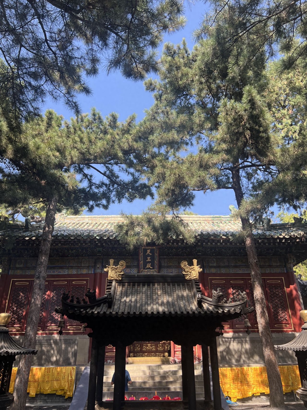 Photo by Tanzhe Temple - Capture the architecture of the Heavenly Kings Hall with incense burners and pine trees.