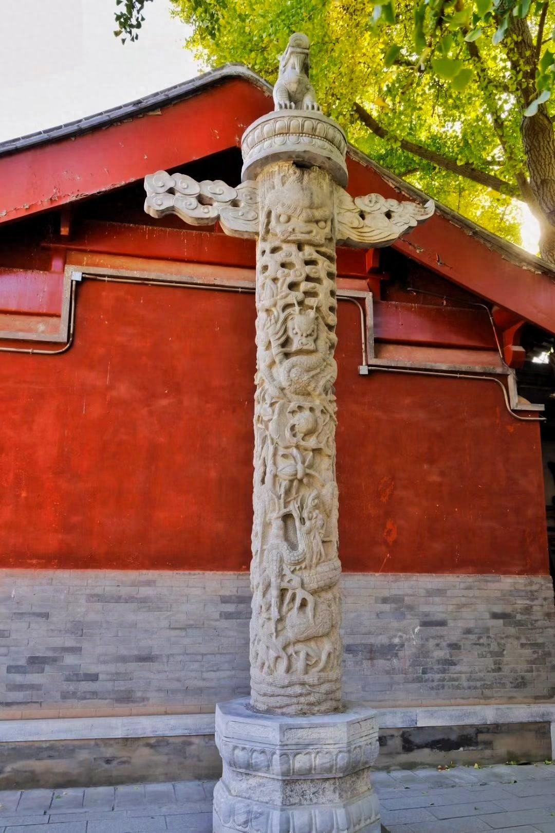 Photo by Beijing Stone Carving Art Museum - Stone Sculpture Pillars, Red Walls, and Trees