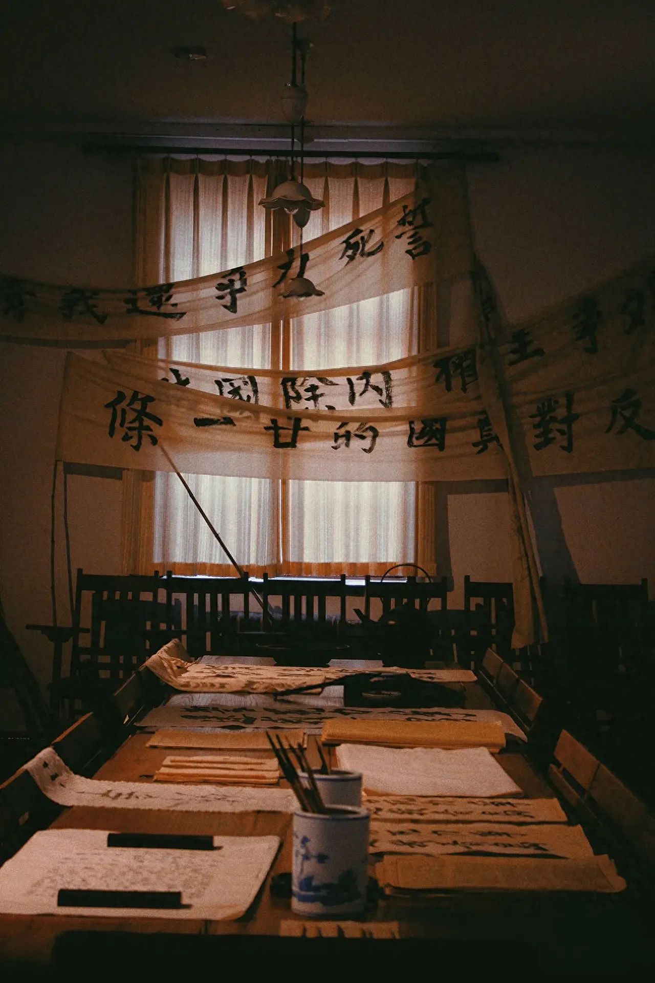 1. Perspective: The photographer stands at one end of the long table indoors, capturing the scene from an eye-level angle.
2. Composition technique: A combination of vertical and horizontal line compositions is utilized, with the horizontal banner hanging vertically and the table extending horizontally, enhancing the stability of the image.
3. Lens application: A standard lens is used to accurately reproduce the proportions of the indoor space and the actual size of objects, resulting in a natural visual effect.
Admission fee: Free, but reservation is required.
Other tips: The visiting area consists of three levels, each with guides directing the visiting order. It is best to follow the orderly number plates at the entrance. Photography is allowed but videotaping is not. You can view the exhibition online through the Peking University Red Building WeChat public account, and there are QR codes inside the exhibition hall that you can scan to listen to audio explanations.