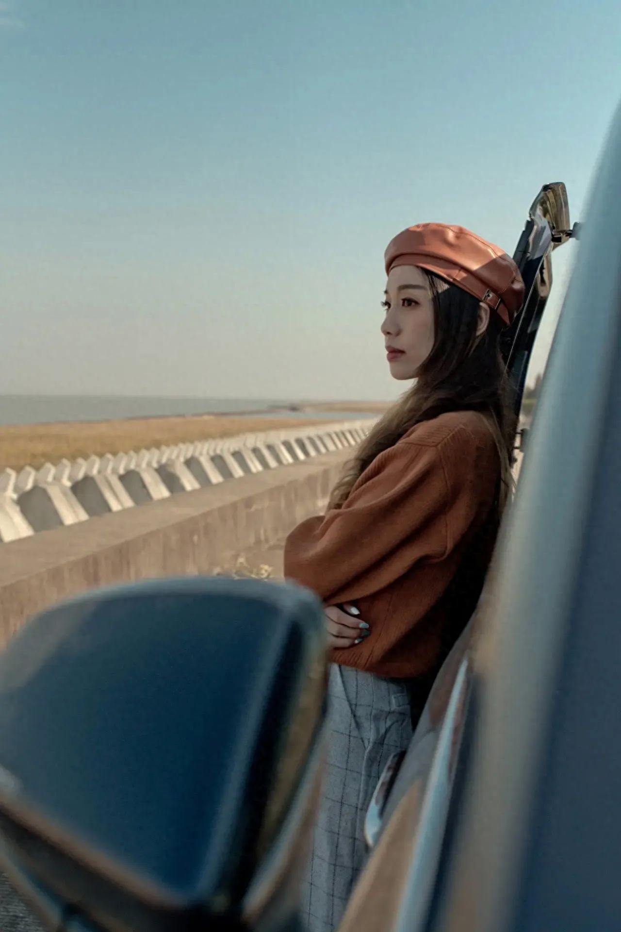 1. Angle of Position: The photographer stands in front of and slightly to the side of the model, taking a photo from a low angle looking up.

2. Composition Technique: Utilize foreground composition with the car's rearview mirror as the foreground to enhance the sense of depth and spatiality in the image.

3. Lens Usage: Employ a mid-telephoto lens to compress space, making the background simpler and emphasizing the main subject of the person.

Travel Tips: It is recommended to self-drive to the island, where the car can be directly driven onto the ferry for a fee of 40 yuan per vehicle, plus an additional 5 yuan for each passenger except the driver. The road that extends into the sea is located at the intersection of Dongjiang Road and Xinyao Road on Hengsha Island, where there is a sign for a project department. Follow the road straight to the end to reach the seaside road. It is suggested to arrive about 40 minutes before sunset.
