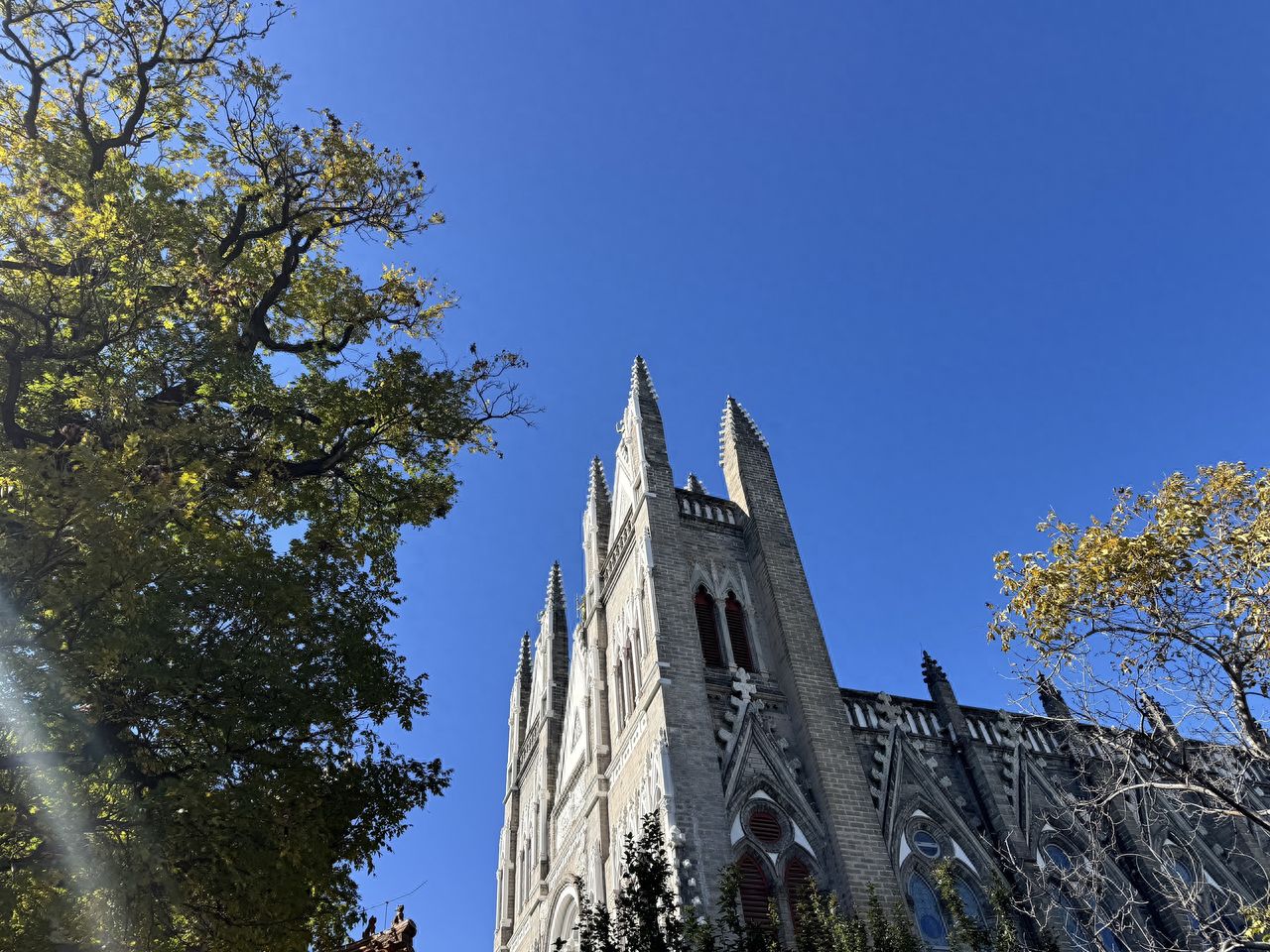 Photo by Xishiku Catholic Church - Church spire with Gothic architecture and trees