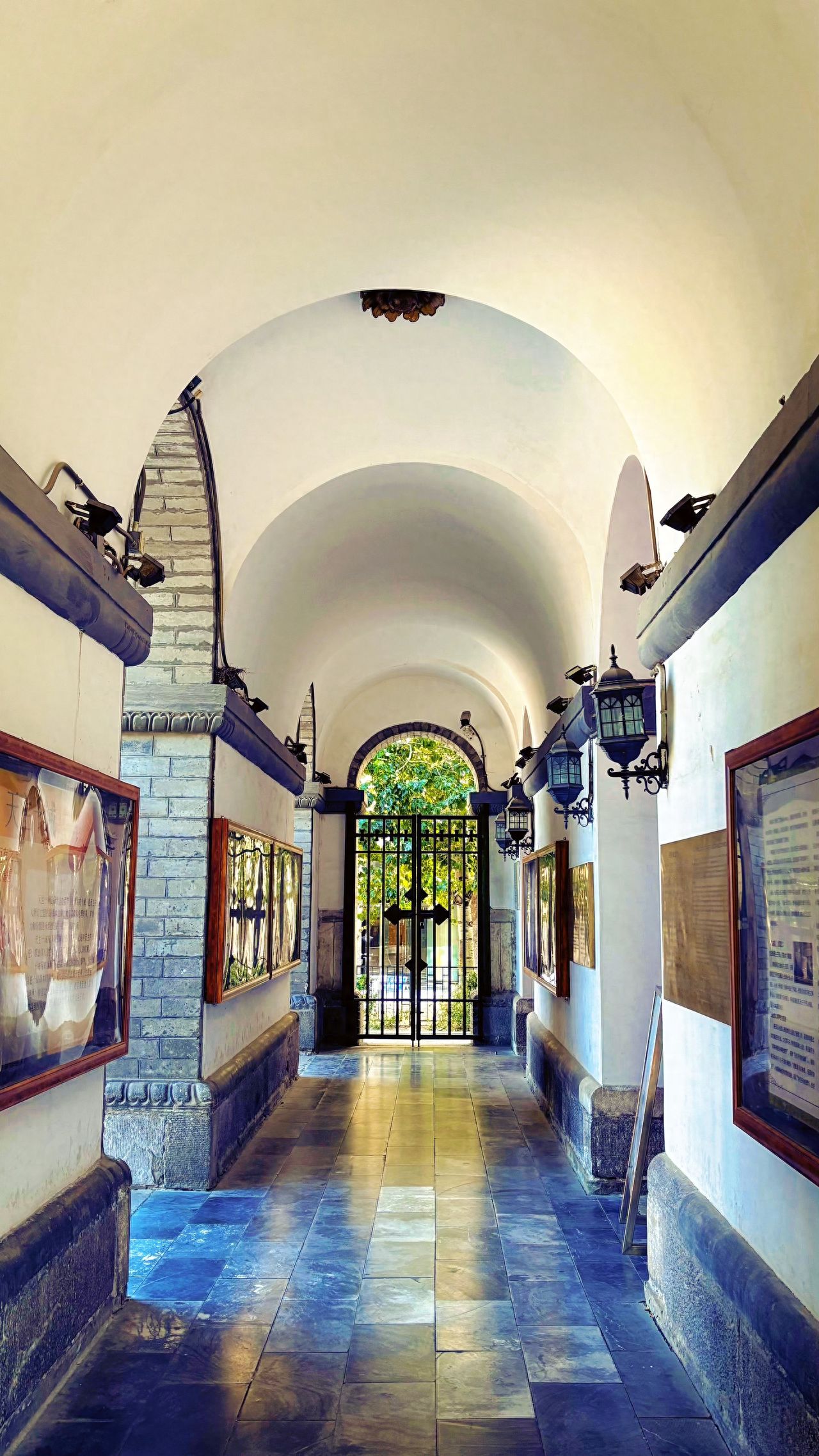 Photo by Wangfujing Catholic Church - Arched interior corridor with stone slab road and iron gate.