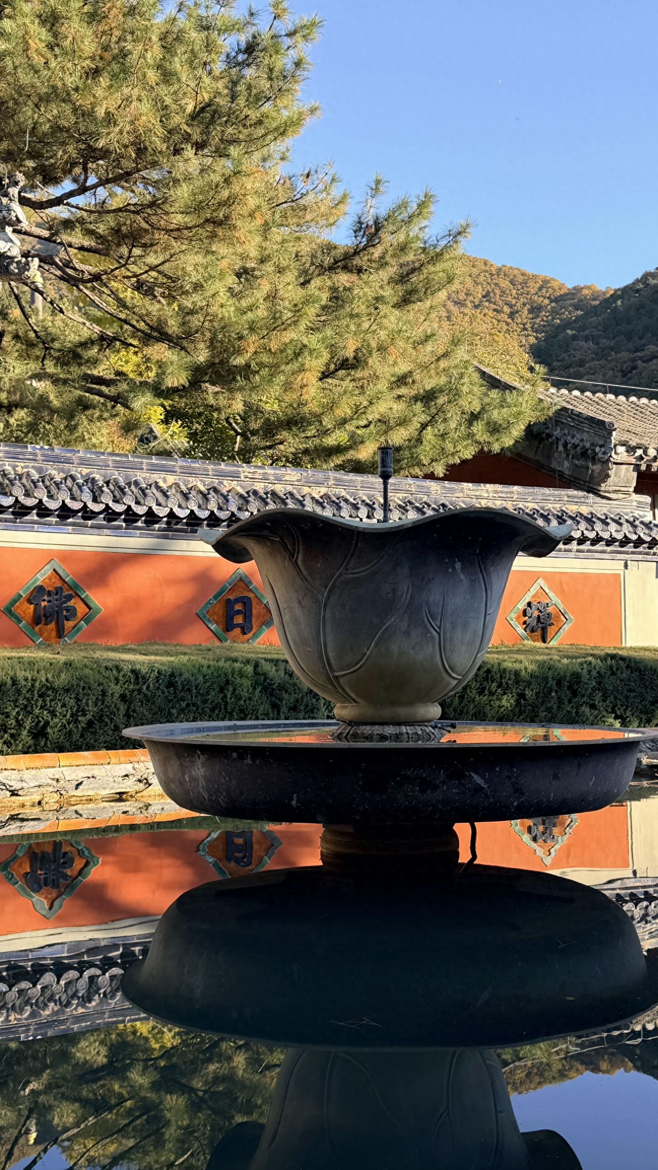 Photo by Tanzhe Temple - Stone basin pool with inscriptions, red walls, and trees